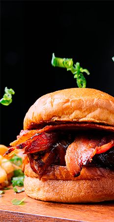close-vertical-de-um-hamburguer-saboroso-com-bacon-em-uma-parede-preta